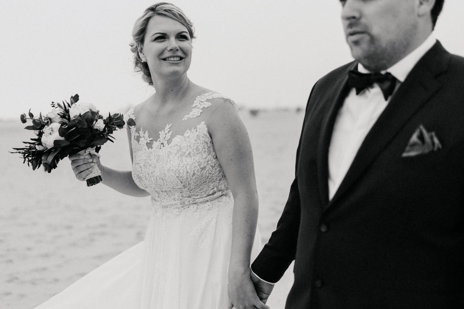 Braut und Bräutigam gehen Hand in Hand am Strand von Sankt Peter-Ording