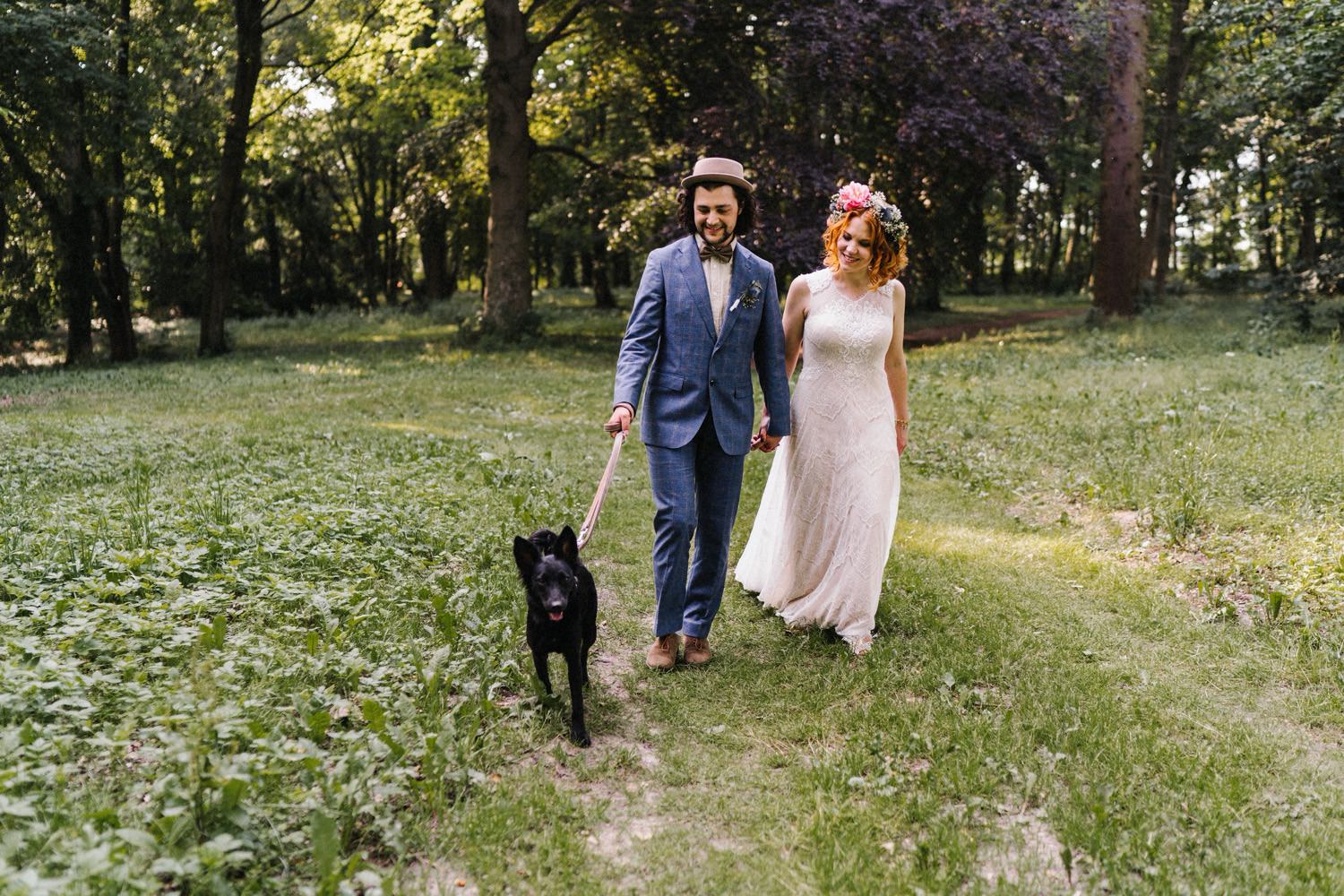 Das Brautpaar geht mit ihrem Hund durch den Wald