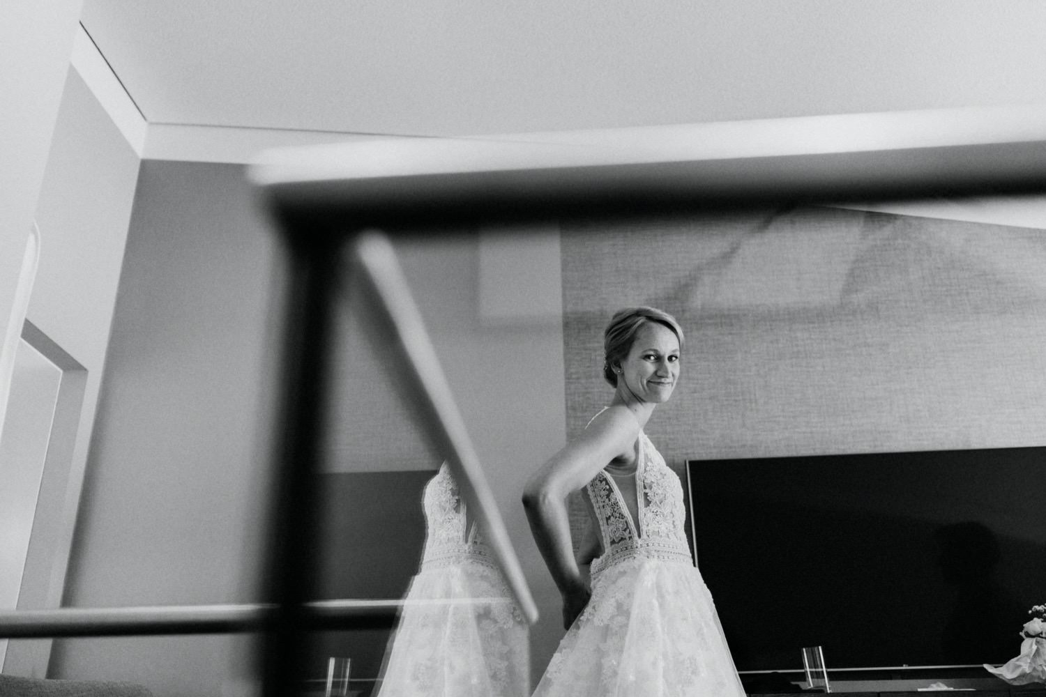 Die Braut in ihrem Brautkleid mit viel Spitze beim fertig machen im Hotelzimmer des Royal Meridian