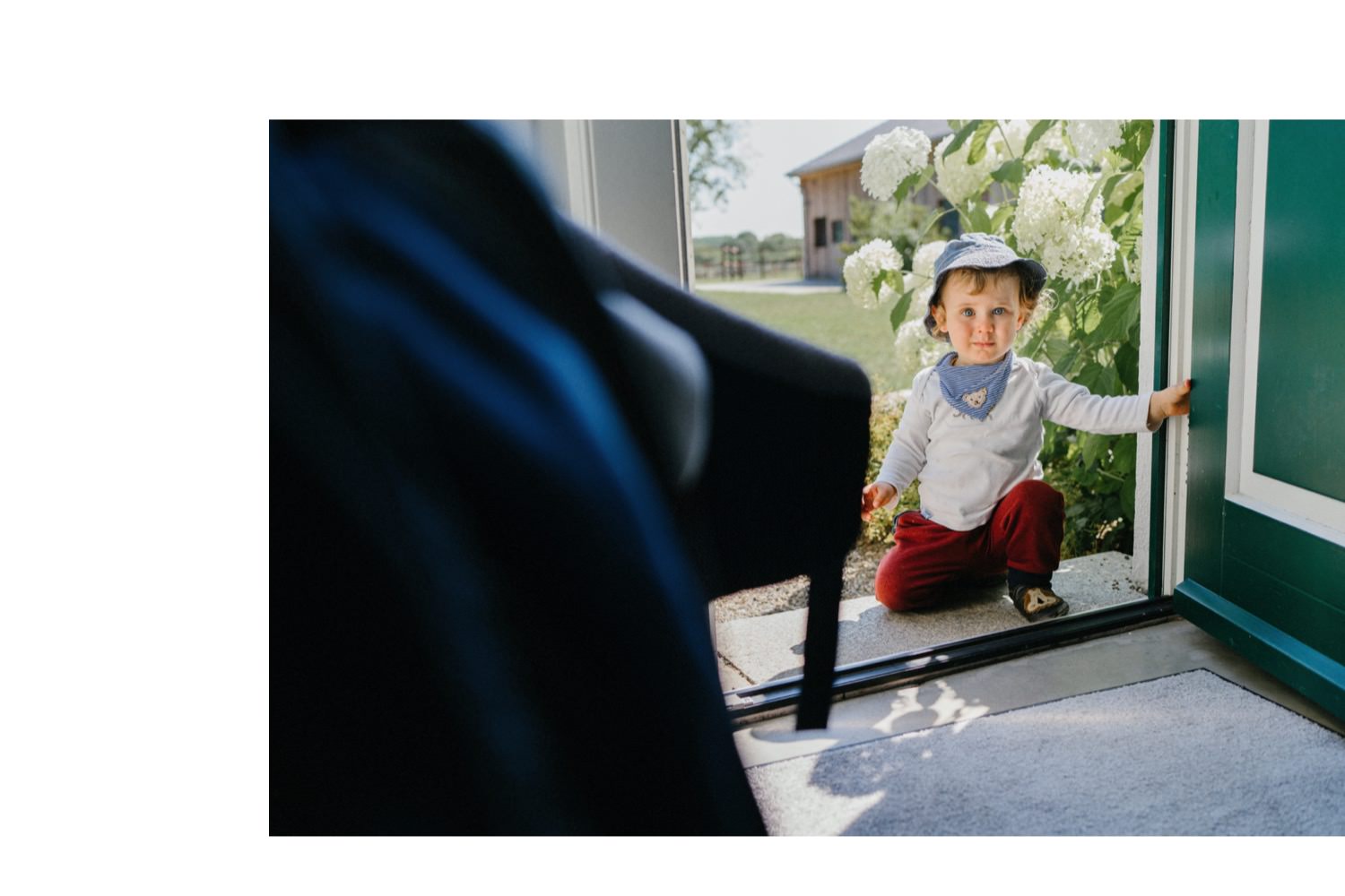 Ein kleines Kind sitzt an der Türschwelle des Ferienhauses