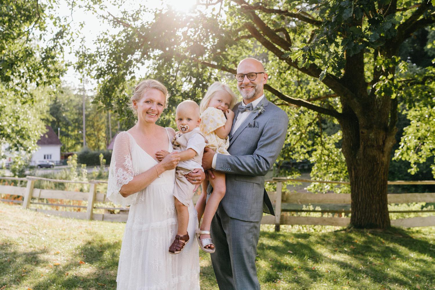 Familienfoto eines Brautpaares mit deren zwei Kindern im Gegenlicht im Garten des Forsthaus Friedrichsruh bei Hamburg aufgenommen vom Hochzeitsfotografen Bergedorf Till Gläser