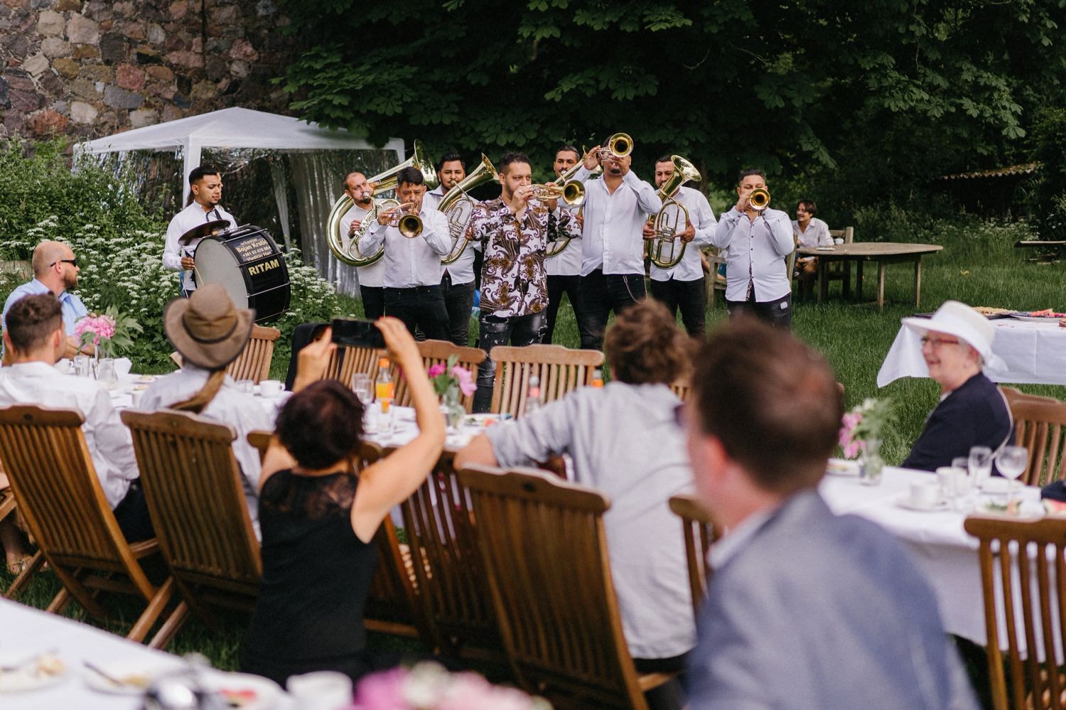 Eine Blaskapelle vom Balkan beginnt am Nachmittag zu spielen und verbreitet sofort eine ausgelassene Stimmung. Mit ihren mitreißenden Melodien und ihrem energiegeladenen Rhythmus bringen sie die Gäste zum Tanzen und Feiern, während sie die festliche Atmosphäre der Hochzeit weiter anheizen.