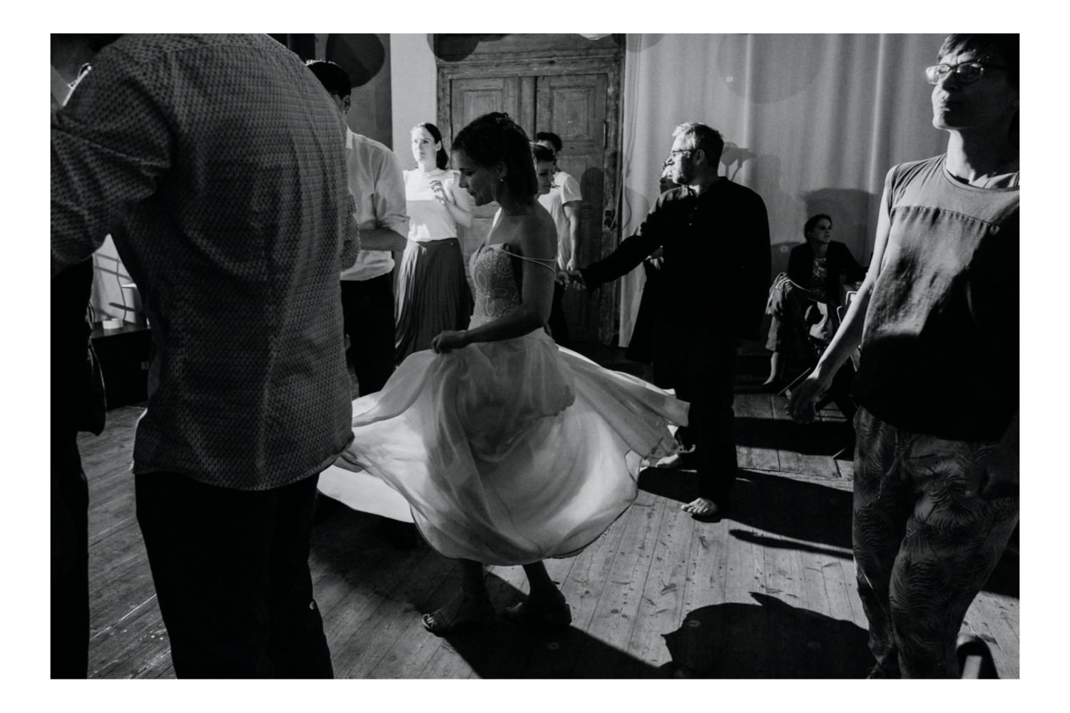 Die Braut tanzt zur mitreißenden Musik der Band so ausgelassen, dass ihr Kleid beginnt zu fliegen, während sie sich im Rhythmus der Musik dreht. Ihr strahlendes Lächeln und die Freude in ihren Augen spiegeln die Atmosphäre der Feier wider, während sie die Tanzfläche mit Energie und Leidenschaft erfüllt. Die Gäste jubeln ihr zu und genießen den Moment, während das Brautpaar und ihre Liebsten gemeinsam diesen besonderen Tag feiern.