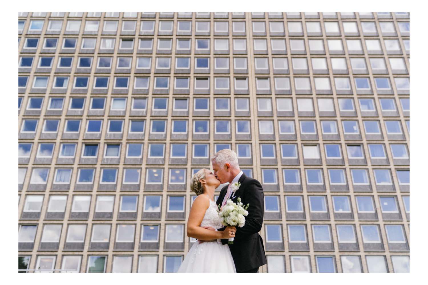 Das Brautpaar beim Portraitshooting vor der Bauhausfassade des Hochhauses des Bezirksamt Eimsbüttel bei der Hochzeit in Hamburg