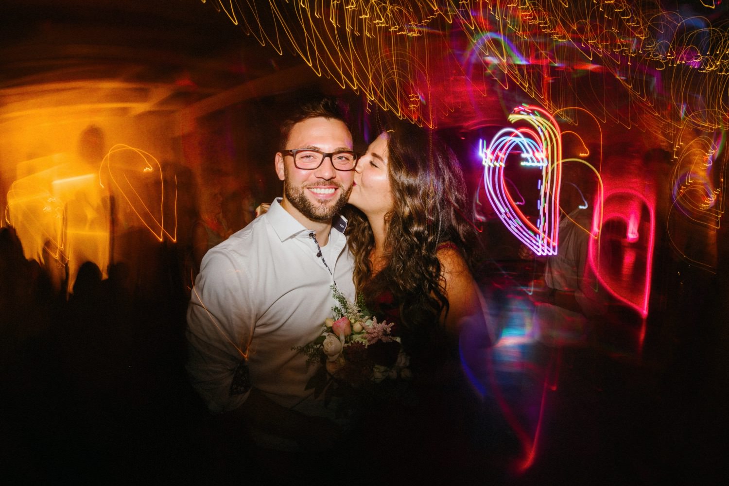 Die Hochzeitsgäste tanzen im Lichtermeer und lassen sich von den Effektlampen in eine Welt voller Magie und Glanz entführen. Die Langzeitbelichtung enthüllt die Schönheit und Lebendigkeit dieses unvergesslichen Augenblicks auf der Tanzfläche.