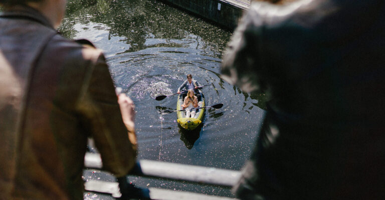 Das Brautpaar fährt bei ihrer Corona Hochzeit in einem Kanu auf dem Isebekkanal auf einer Brücke stehen Freunde und gratulieren dem Paar